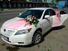 a white car decorated with pink and white flowers