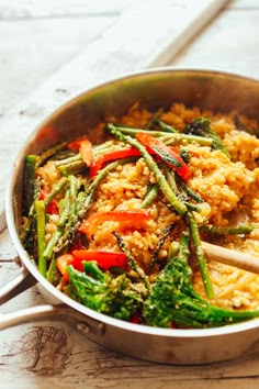 a pan filled with rice and vegetables on top of a wooden table