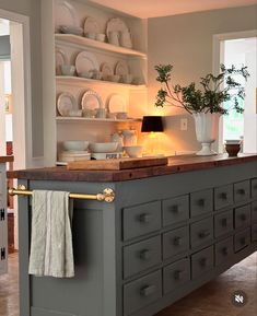 a large kitchen island with lots of dishes on it's shelves and cupboards