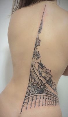 a woman's back with a tattoo on her lower half and the top part of her stomach