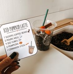 a person holding up a sign that says iced pumpkin latte with coffee beans and cinnamon sticks