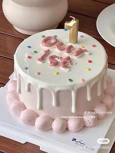 a white cake with pink frosting and sprinkles on it, sitting on a table