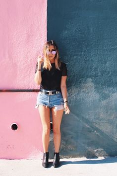 a woman leaning against a pink and blue wall