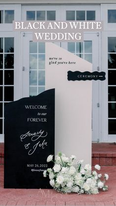 a welcome sign and flowers on the ground in front of a building with large windows