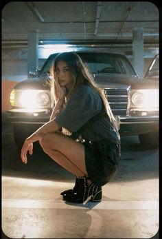 a woman kneeling down in front of a car