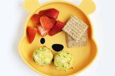 a yellow plate with some food on it and strawberries in the shape of a bear