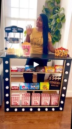 a woman with long hair standing in front of a shelf filled with food and snacks