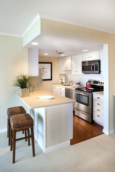 a kitchen with an island and two stools next to the counter top in front of it