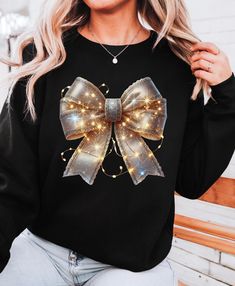 This cozy Gold Bow with lights Christmas bow sweatshirt exudes holiday cheer and warmth. Perfect for the festive season, it brings a touch of holiday magic to your wardrobe. Ideal for those seeking a comfy yet stylish option to wear during the winter months. Product features - Made with a cozy medium-heavy fabric blend of cotton and polyester - Classic fit with crew neckline for a comfy wearing experience - Double-needle stitching for top-tier durability - Gray, pearlized tear-away label for itc Christmas Party Crew Neck Sweater, Winter Party Sweatshirt With Crew Neck, Winter Party Crew Neck Sweatshirt, Bow Sweatshirt, Winter Lights, Bow Christmas, Winter Light, Lights Christmas, Christmas Bow