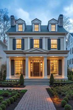 a large white house with black shutters on the front and side windows at night