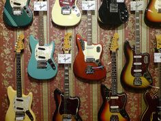 many guitars are lined up on the wall