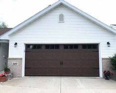 a white house with two brown garage doors