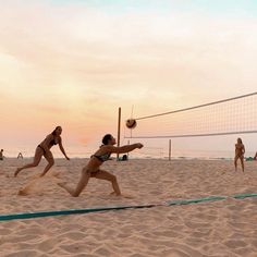 two women are playing volleyball on the beach at sunset, while other people play volley ball in the background