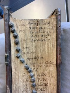 an old book with writing on it and beads attached to the front cover is sitting on a couch