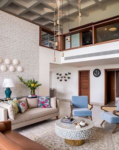 a living room filled with furniture next to a tall white brick wall and ceiling fan