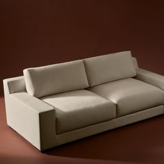 a white couch sitting on top of a brown floor next to a red wall in a room