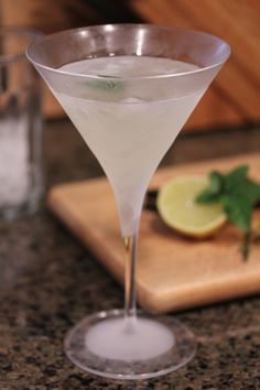 a martini sitting on top of a counter next to a cutting board