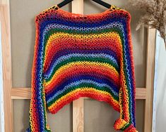 a colorful crocheted sweater hanging on a wooden hanger in front of a door