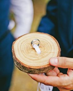 a person holding a piece of wood with a wedding ring on it's finger