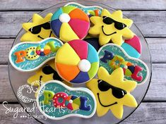 decorated cookies in the shape of sunflowers and beach balls on a glass plate