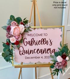 a welcome sign with flowers and greenery hanging from it's frame in front of a door