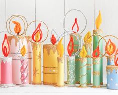 several colorful candles are lined up on a white surface with gold and red decorations around them