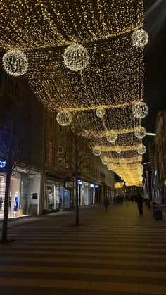 people walking down a street covered in christmas lights