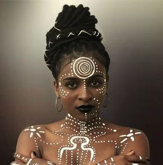 a woman with white paint on her face and body is standing in front of a dark background