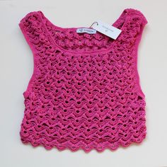 a pink crocheted top with a tag on it