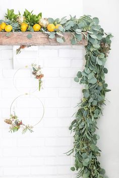 a white brick wall with greenery and lemons hanging on the mantle above it