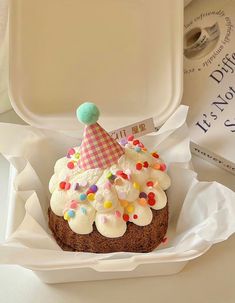 a cupcake in a paper container with a party hat on top