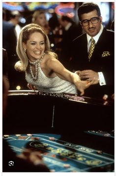 a man and woman are playing roulege in a casino room with other people