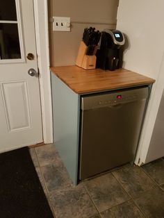 a dishwasher sitting on top of a wooden counter next to a white door