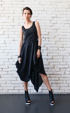 a woman standing in front of a white brick wall wearing a black dress and high heels