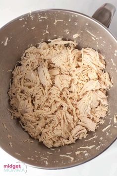 a metal bowl filled with shredded chicken on top of a stove