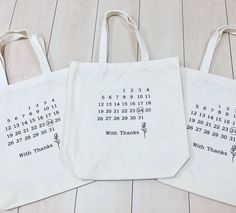 three white shopping bags sitting on top of a wooden floor next to eachother