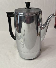 a silver tea pot with a black handle