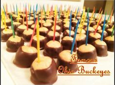 chocolate covered candies with colorful sticks sticking out of them on a white tablecloth