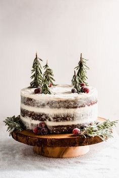 a cake with frosting and pine trees on top sitting on a wooden platter