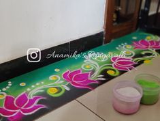 two plastic cups sitting on top of a counter next to a wall with flowers painted on it