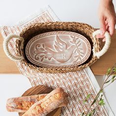 someone is holding a tray with bread in it on a table next to other items