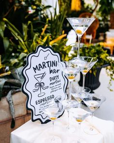 martini bar sign sitting on top of a table next to glasses filled with drinks and garnishes