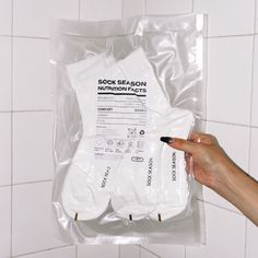 someone is holding up a package of socks in the bathroom with instructions on how to use them