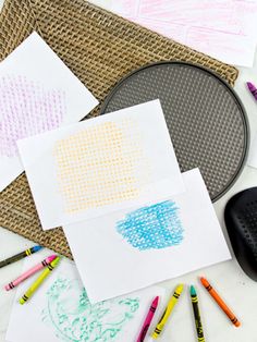 some colored crayons are on the table next to paper and pencils that have been drawn