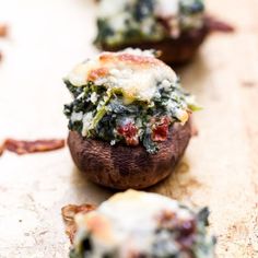 baked stuffed mushrooms with spinach and cheese on them sitting on a cutting board next to bacon