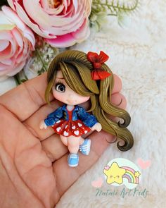 a hand holding a tiny doll with flowers in the background