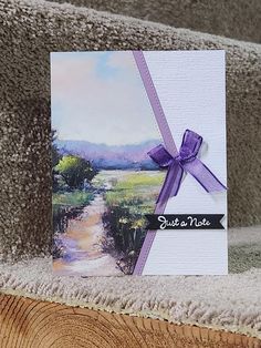 a greeting card with a purple ribbon on top of a wooden table next to a pile of carpet