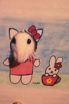 a hamster with a hello kitty drawing on it's wall next to a toy mouse