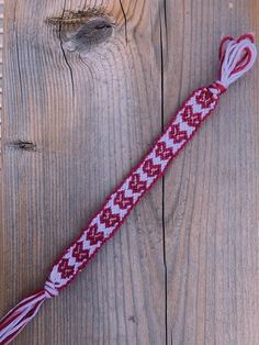 a red and white tie laying on top of a wooden floor next to a piece of wood