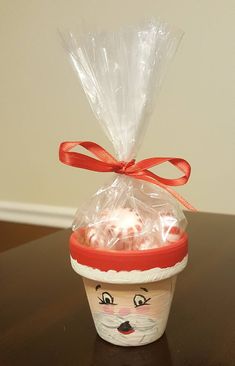 a plastic cup filled with candy and wrapped in cellophane to look like santa claus